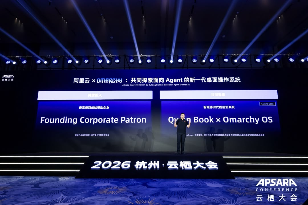 2026年に杭州で開催されたApsara Conferenceのステージ上で、Alibaba CloudによるFounding Corporate PatronコミットメントとOmarchyとのQwen Bookコラボレーションの発表の様子。